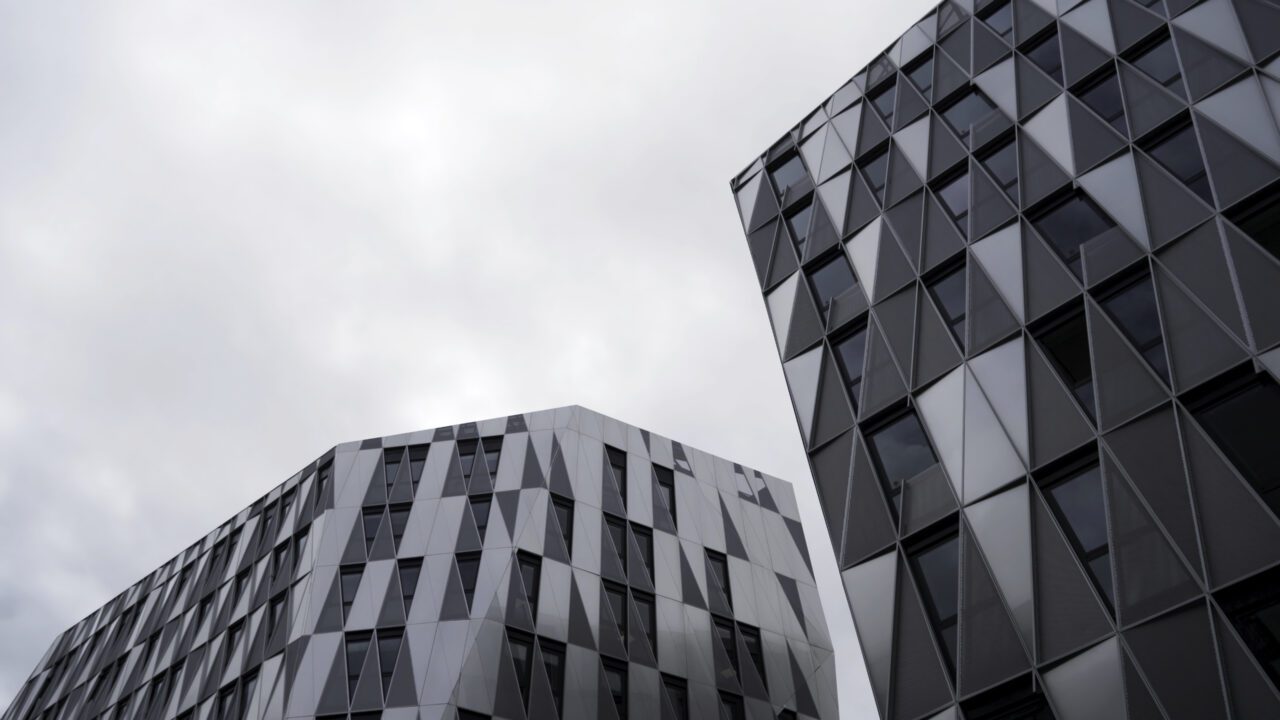 bottom-view-of-modern-unique-building-with-triangle-shaped-windows-of-black-color-on-bright-cloudy-e1695971005517.jpg